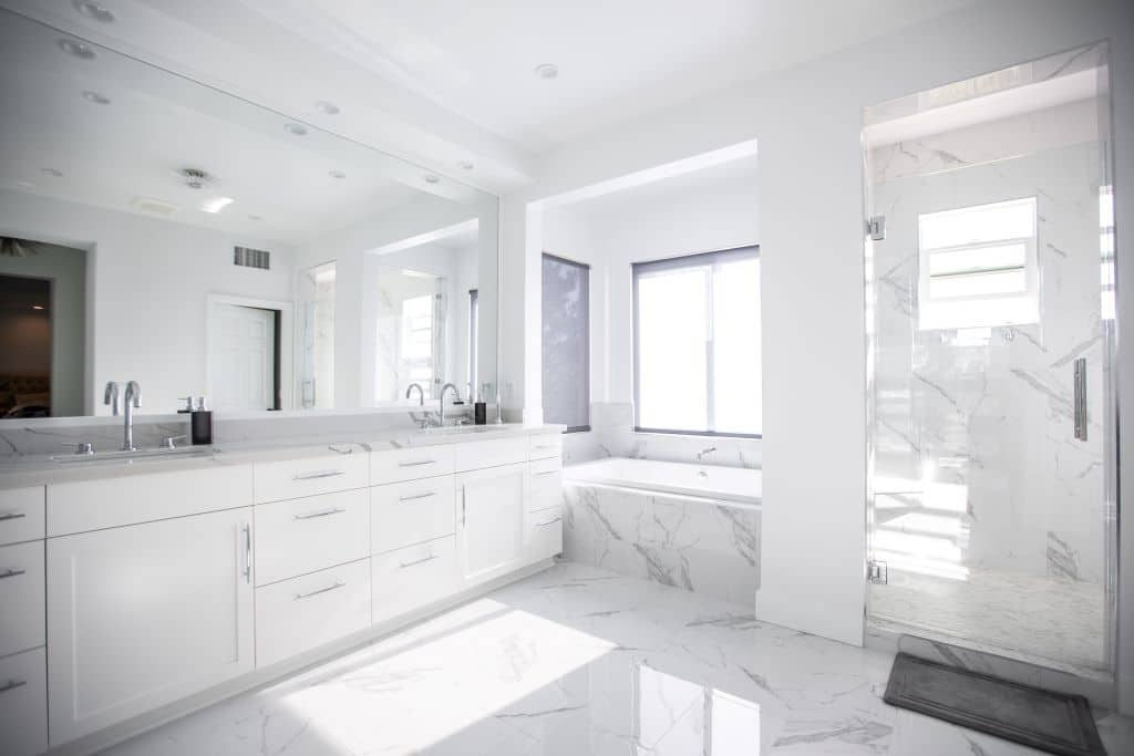 White marble master bathroom with a frameless glass shower