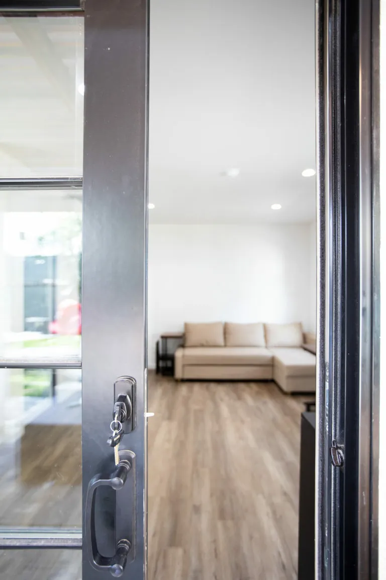 New black-framed entry door opening into a finished garage-conversion living space