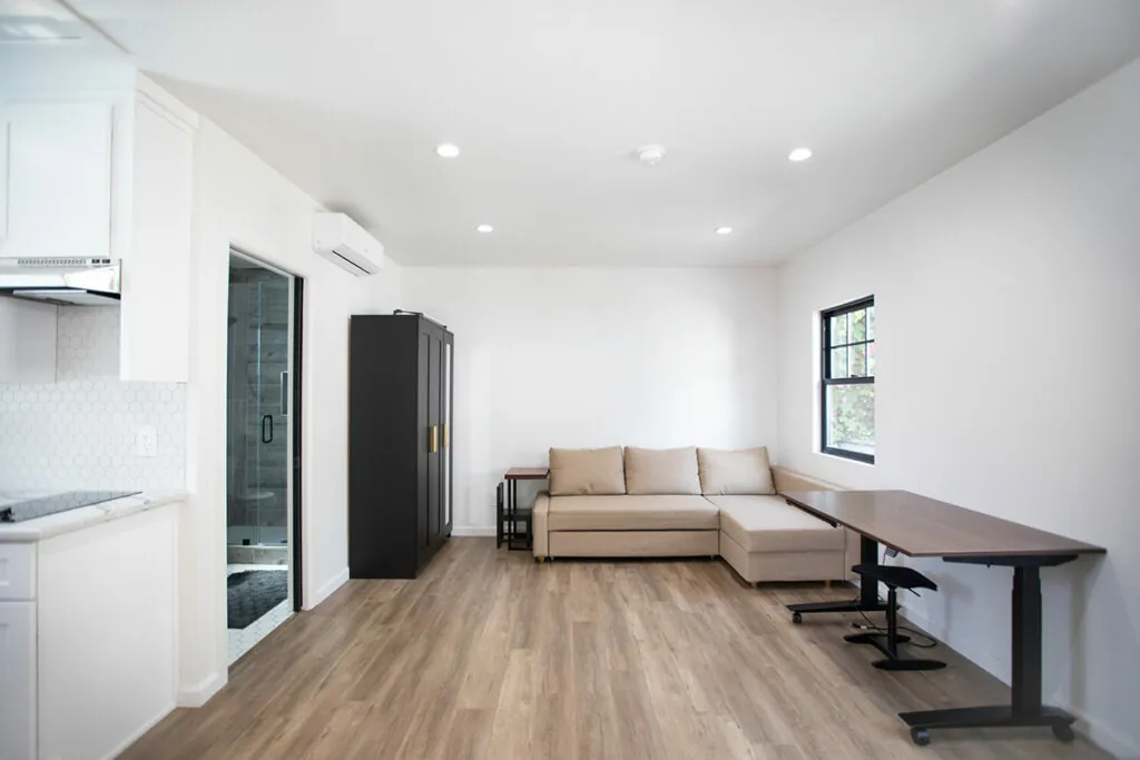 Converted garage interior with a bright living area, kitchenette and standing desk