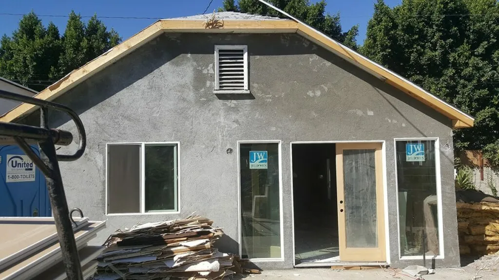 Newly stuccoed garage conversion with fresh windows and a glass patio door