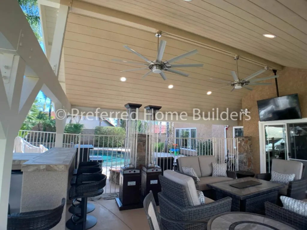 Covered outdoor living area with ceiling fans, lounge seating and a poolside bar