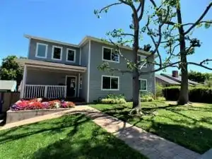 Two-story home addition with new siding, a covered porch and mature landscaping