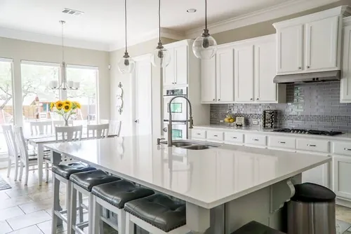 Bright white kitchen with a large quartz island, pendant lighting and bar seating