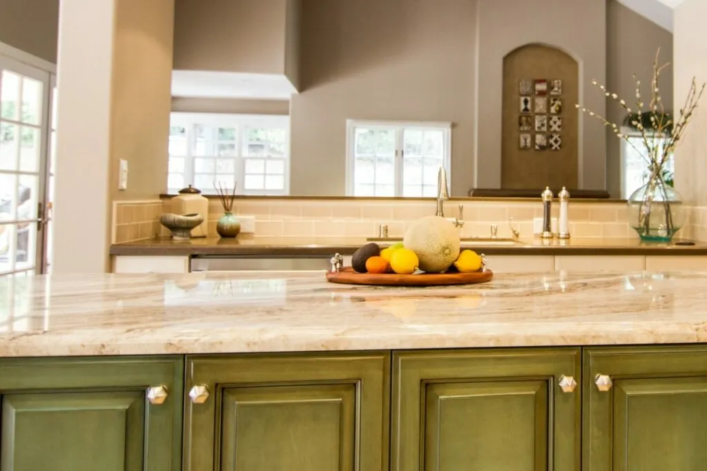 Kitchen island with a marble countertop and green cabinetry