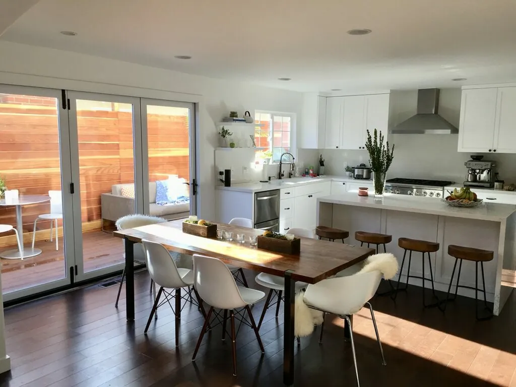 Open-concept kitchen and dining area with a wood table and white cabinetry